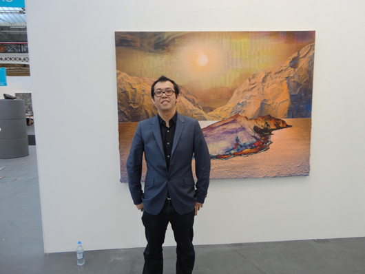 London-based artist Gordon Cheung with one of his large collage-based works on the stand of London dealers Edel Asanti at ART14 London. Image Auction Central News.